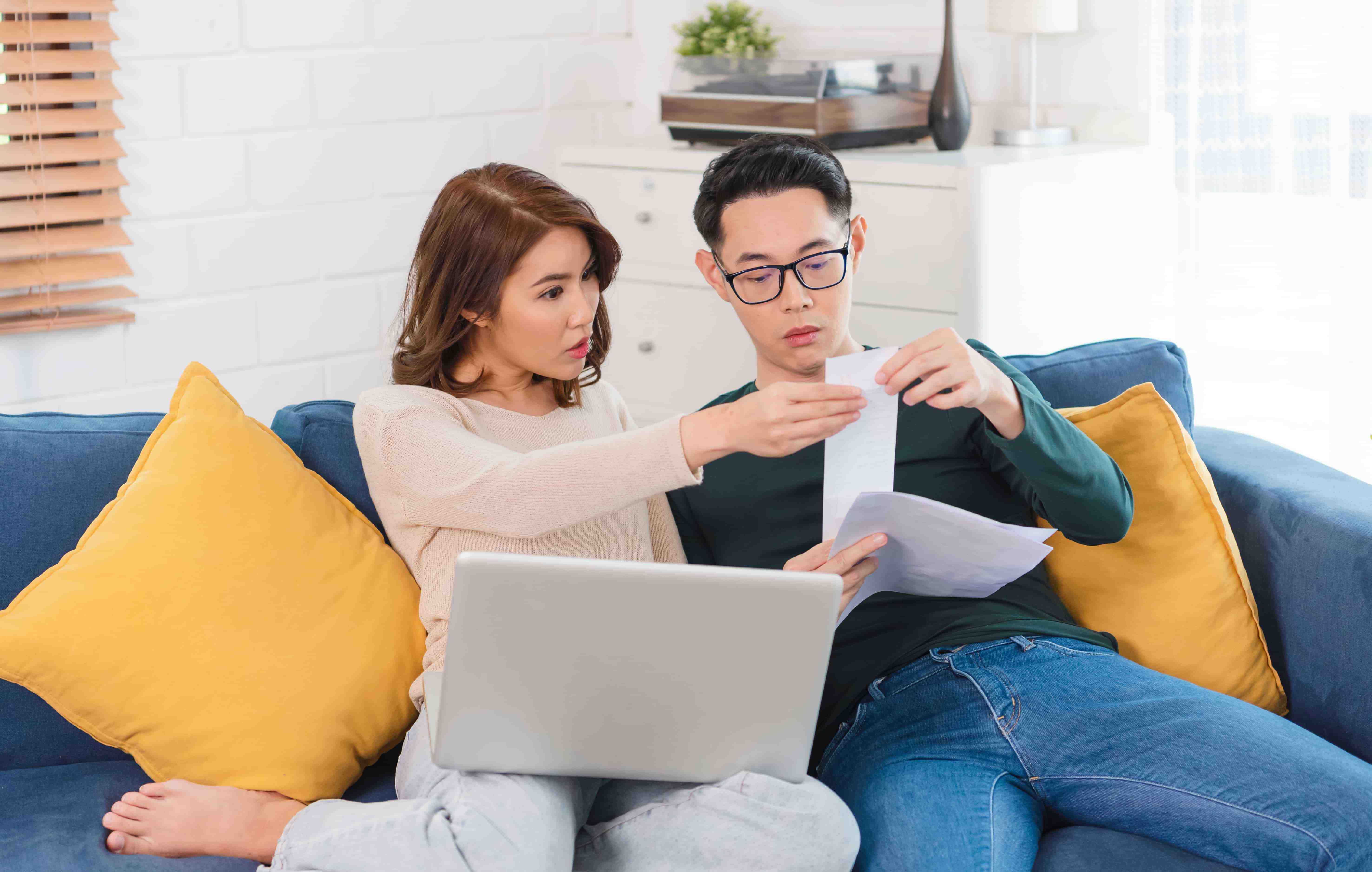 serious asian husband checking analyzing statement utilities bills sitting together home  2 